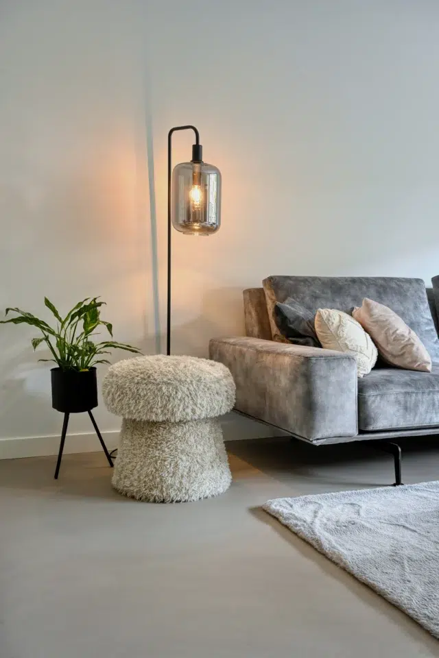 Lavasteen gietvloer in een woonkamer met grijze bank en vloerlamp