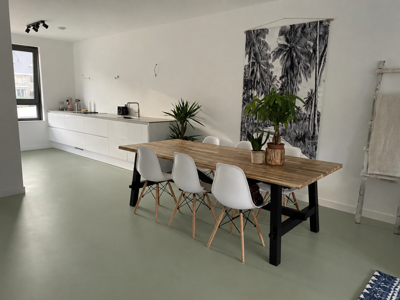 Lichte woonkeuken met houten eettafel en een groene gietvloer.