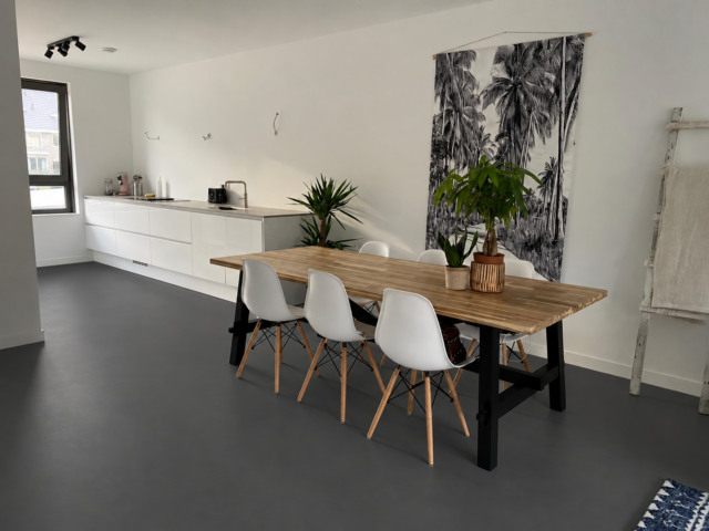 Antraciet gietvloer in een moderne keuken met houten eettafel
